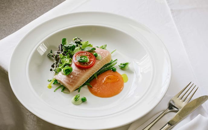 Gegarter Bachsaibling auf Paradeisercoulis mit marinierten Erbsen, Wirtshaus-Rezept, Kräuter, Teller, Besteck, Tischdecke