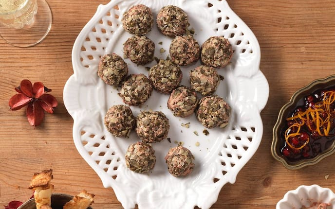 Hühnerleberpralinen, Hühnerleber, Kürbiskerne, Preiselbeeren, Preiselbeerkompott, Orangenzesten, Teller, Holztisch