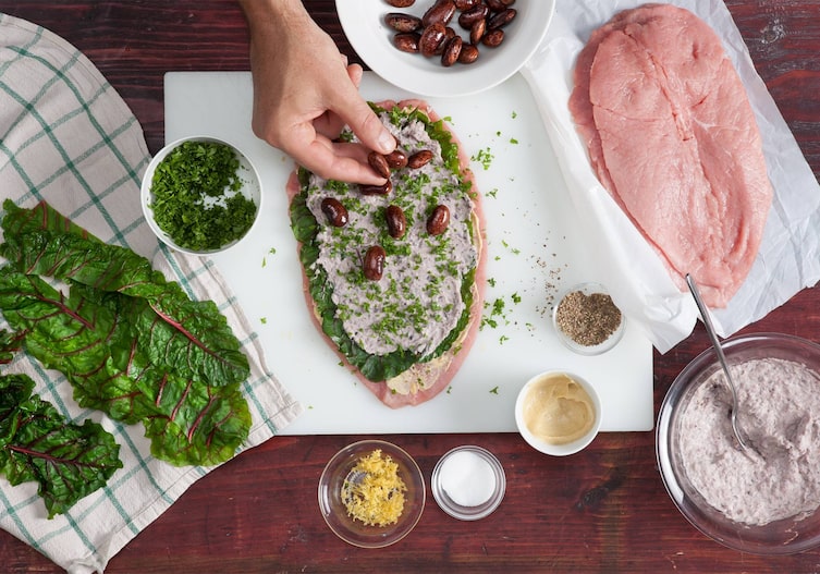 Mangold, Geschirrtuch, Petersilie, Bohnen, Kalbsschnitzel, Schüsseln, Löffel, Brett, Hand