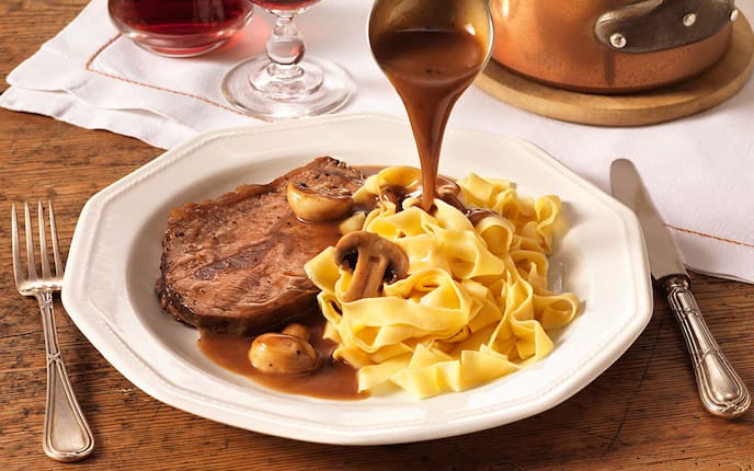 Rindsbraten mit Champignons und Bandnudeln, Sauce, Zweigelt, Weinglas, Gedeck, Holztisch, Kochtopf, Tischdecke