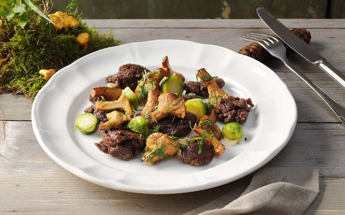 Marinierte Eierschwammerl mit Heidensterz und Kohlsprossen, Moos, Holztisch, Zapfen, Petersilie, Serviette, Teller, Besteck