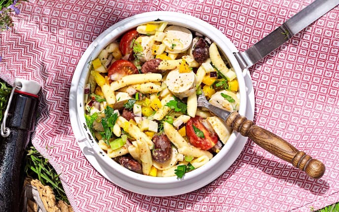 Nudelsalat mit Würstel, Teller, Pfanne, Gabel, Tomaten, Petersilie, Küchentuch, Gras, Flasche, Paprika