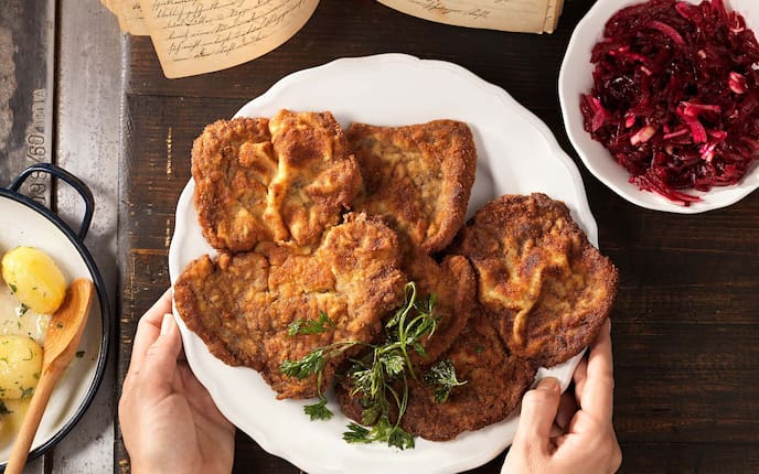 Gebackener Rostbraten, Salzerdäpfel, Rote-Rüben-Salat, Teller, Hände, Holzofen, Kochbuch
