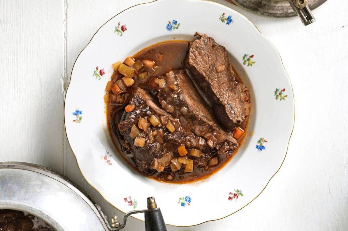 Geblümter tiefer Teller, Rindfleisch mit Saft und Gemüsewürferl, daneben steht ein uralter Kelomat mit dem restlichen Schmorgericht