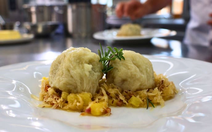Knödel im Strudelteig auf Speckkraut gebettet.