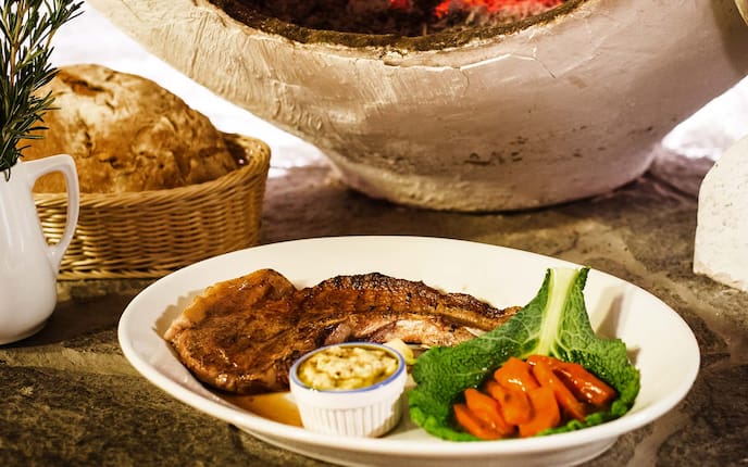 Bergschwein-Kotelett mit Gewürzpolenta und karamellisierten Karotten, Holzofen, Brot, Steinplatte