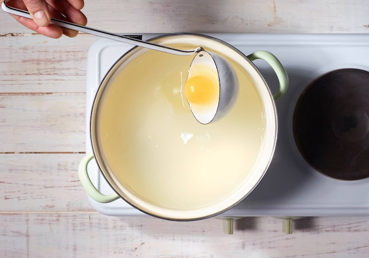 Rohes Ei, Suppenschöpfer, Topf, heißes Wasser, Herdplatte, Ei pochieren