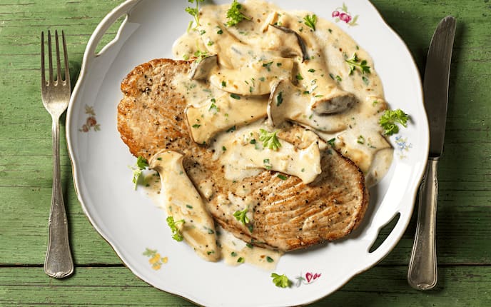 Rahmschnitzel mit Kräuterseitlingen und Karottenreis, Teller, Besteck, Holztisch