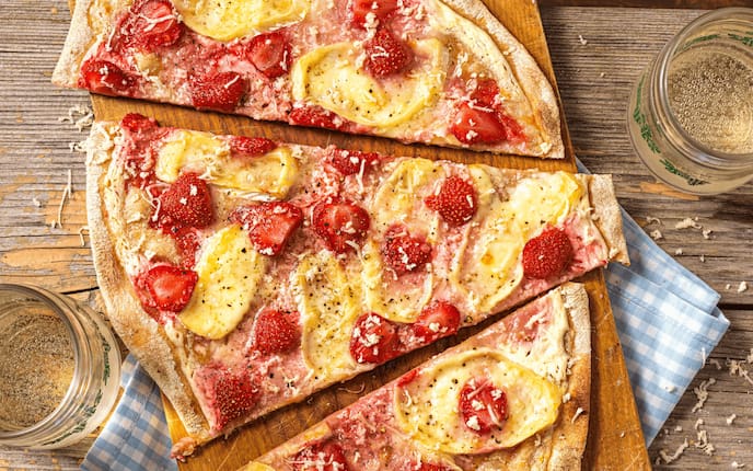 Dinkelfladen mit Schafkäse, Erdbeeren und Kren, Serviette, Glas, Brett, Holztisch