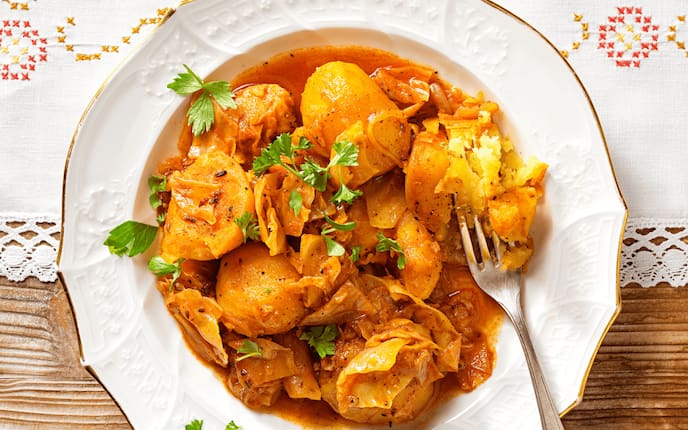 Erdäpfel-Kraut-Gulasch, Petersilie, Teller, Gabel, Tischdecke, Holztisch