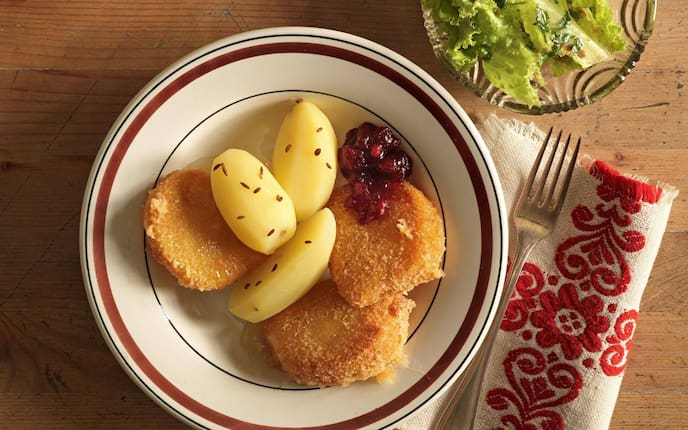 Olmützer Quargel, Preiselbeeren, Salzerdäpfeln, Salat, Gabel, Teller, Serviette, Holztisch