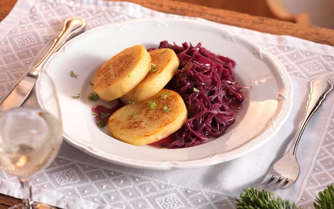 Erdäpfelroulade mit Blaukraut, Weißwein, Gedeck, Kräuter, Tannenzweige, Holztisch