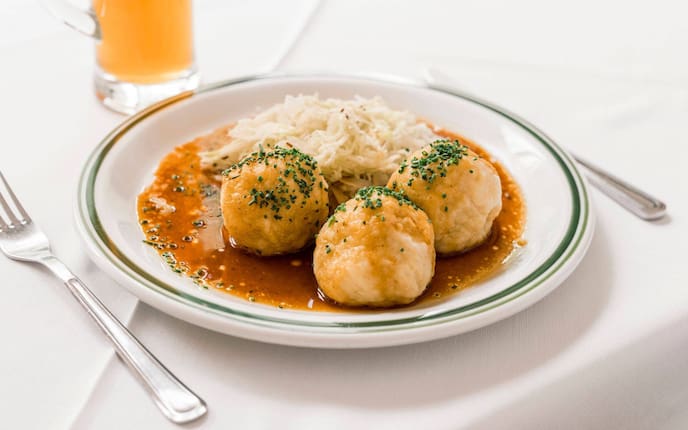 Hascheeknödel, Knödel, Klopse, Kraut, Saft, Schnittlauch, Teller, Gabel, Messer, Tischtuch