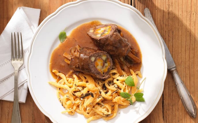 Bergrind, Rouladen, Rahmsauce, Kürbis, Nockerl, Gabel, Messer, Serviette, Besteck