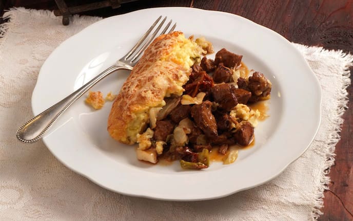 Riebelmais-Auflauf mit Duroc-Schweinsragout, Bregenzerwälder Bergkäse, Gabel, Tischdecke, Kraut