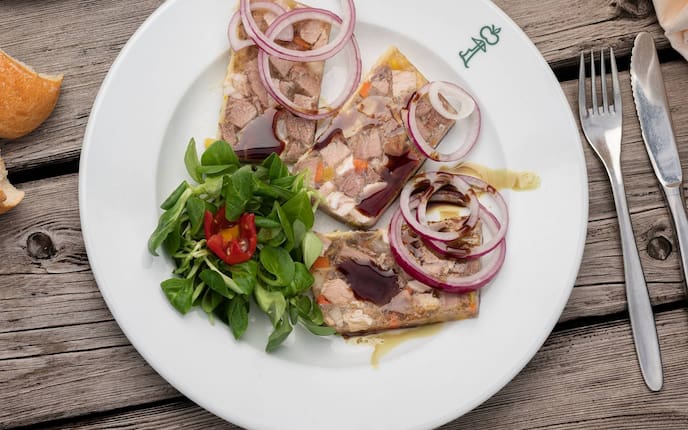 Sulz, Schwein, Zwiebel, Vogerlsalat, Tomate, Besteck, Teller, Holztisch