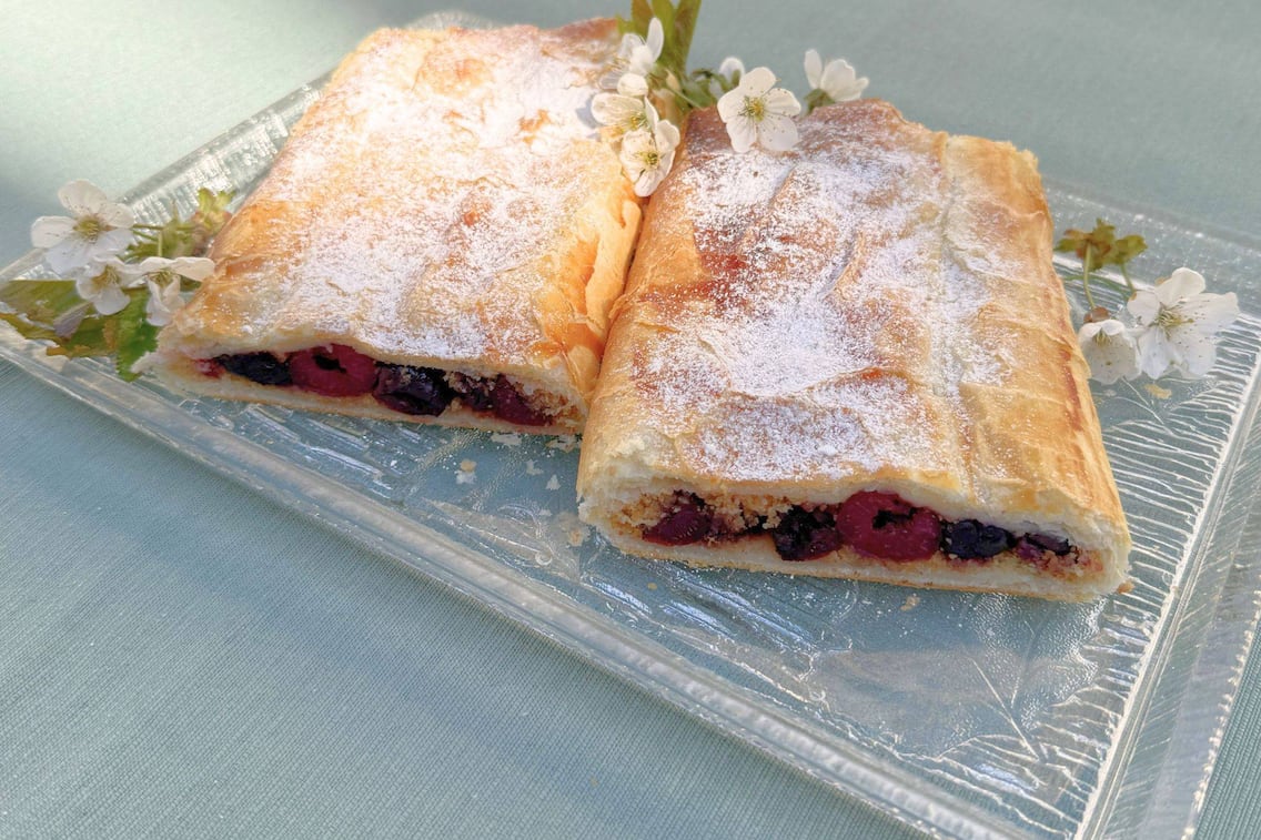 Ein nahes Foto vom Kirschstrudel mit Zucker und Kirschblüten