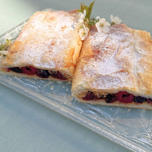Ein nahes Foto vom Kirschstrudel mit Zucker und Kirschblüten