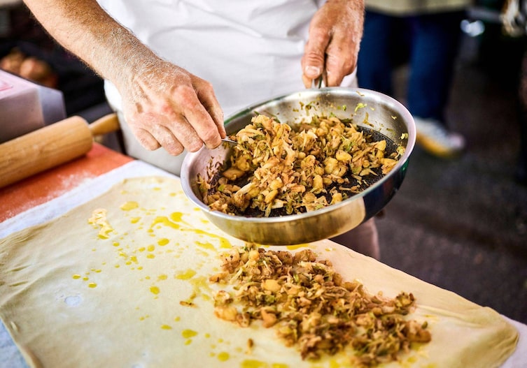 Robert verteilt das Kraut am ausgezogenen Strudel. Das Rezept für den Teig kennt er auswendig, er hat es schon als Kind bei seiner Oma in Kroatien gelernt.