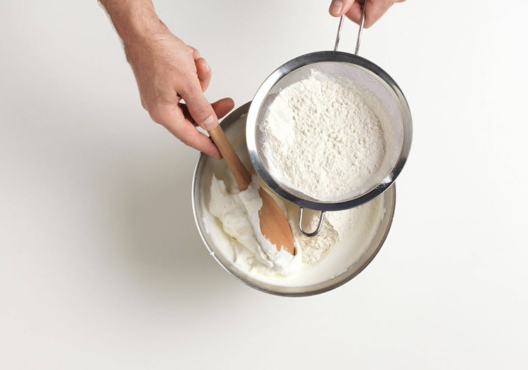 Eischnee unter den durch ein Sieb eine Mehlmischung gehoben wird.