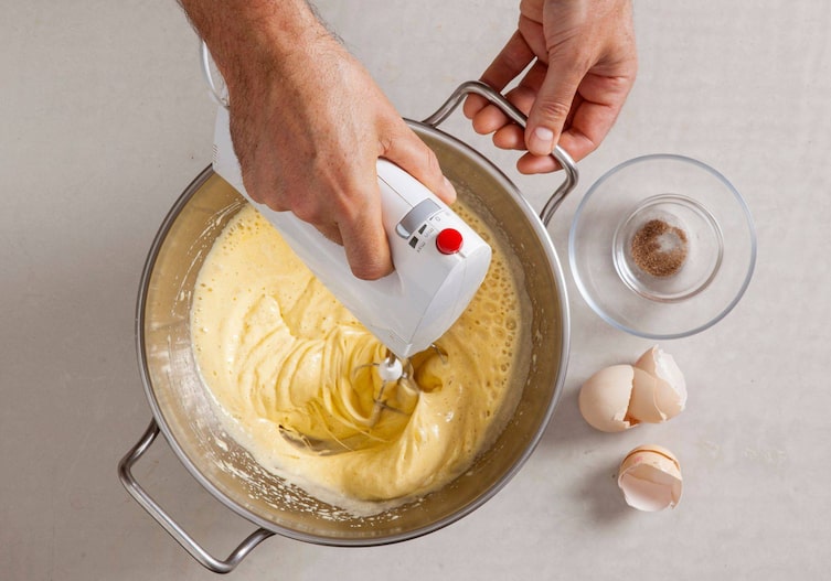 Teig wird mit einem Mixer in der Schüssel cremig gemixt.