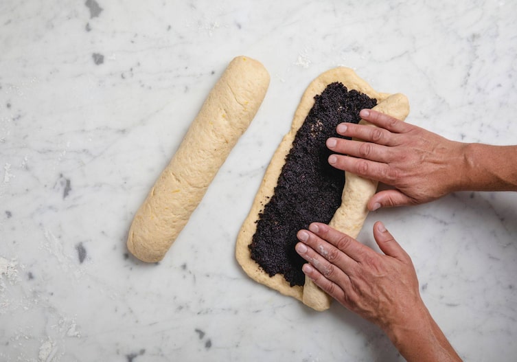 Die gefüllten Teigstücke werden von Hand eingerollt