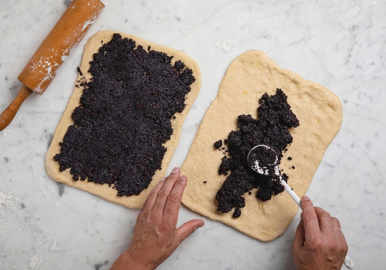 Fertige Füllung wird auf zwei Teigstücke mit einem weißen Kochlöffel aufgetragen.