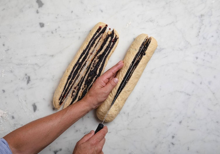 Die beiden Teigstücke werden von Hand mit einem großen Messer mittig auseinandergeschnitten.