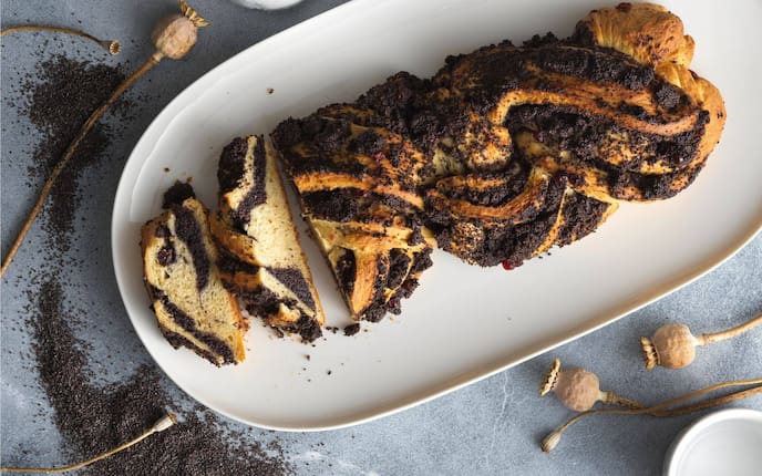 Offen geflochtener Mohnstriezel auf einem weißen Keramik-Servier-Teller