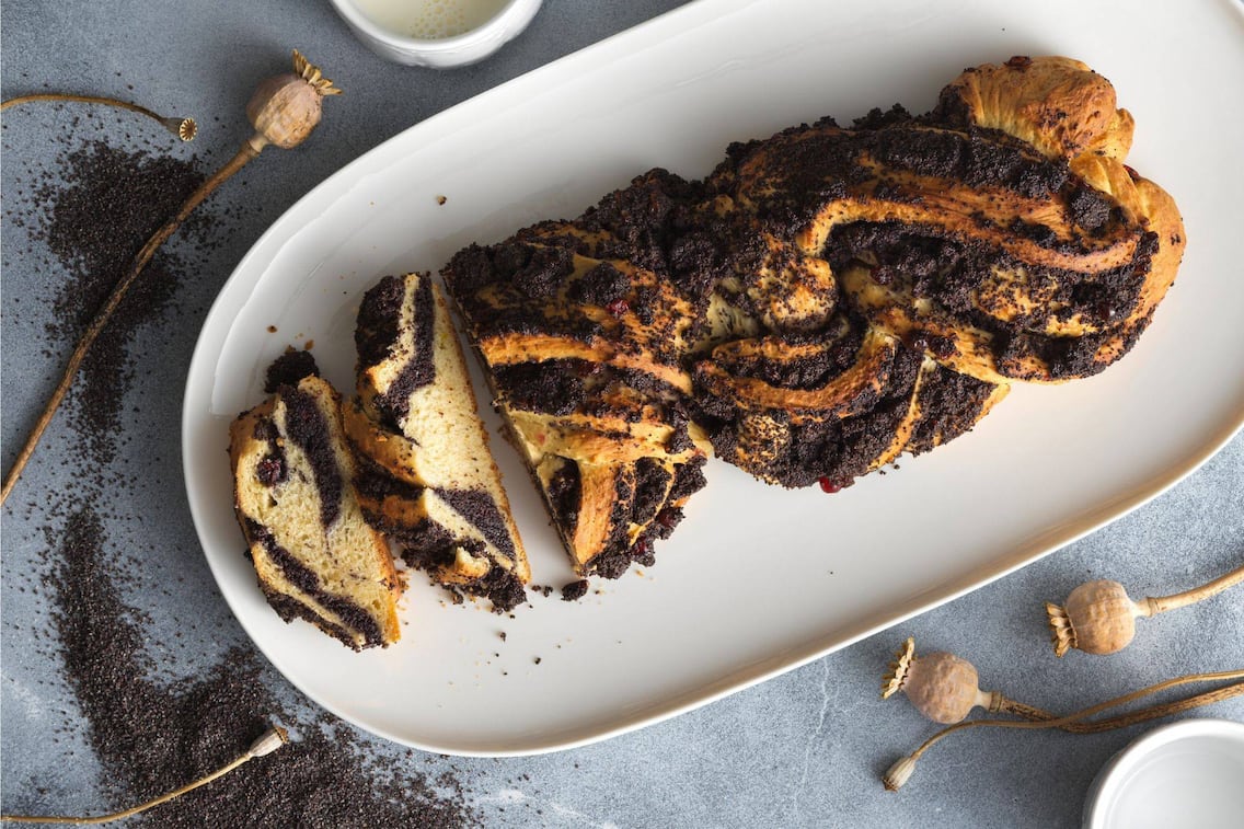 Offen geflochtener Mohnstriezel auf einem weißen Keramik-Servier-Teller