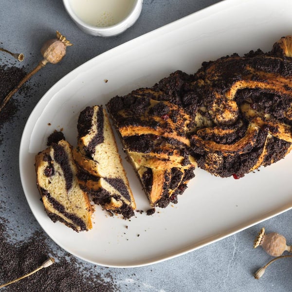 Offen geflochtener Mohnstriezel auf einem weißen Keramik-Servier-Teller