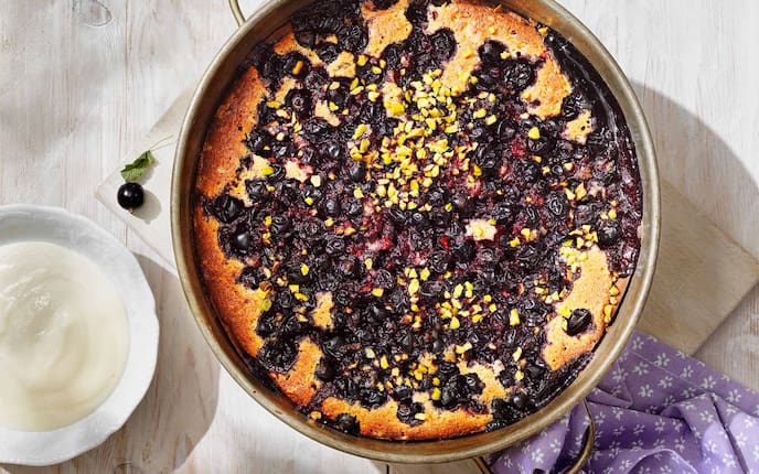 Schwarzer Ribiselkuchen mit Sauerrahm & Pistazien, Holzbrett, Kuchenform, Geschirrtuch, Schüsserl