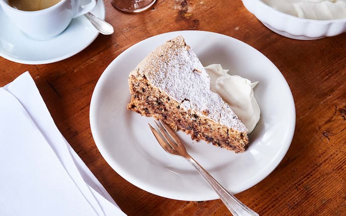 Bosnische Torte mit Haselnüssen und Schokolade, Kaffee, Schlagobers, Holztisch, Staubzucker, Serviette, Gedeck, Nachspeise, Servus Rezept