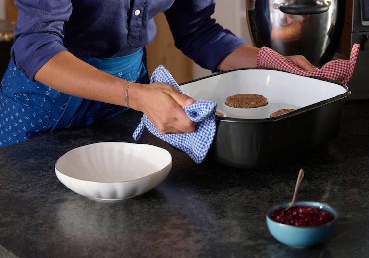 Paula hebt die fertigen Soufflés im Wasserbad aus dem Ofen.