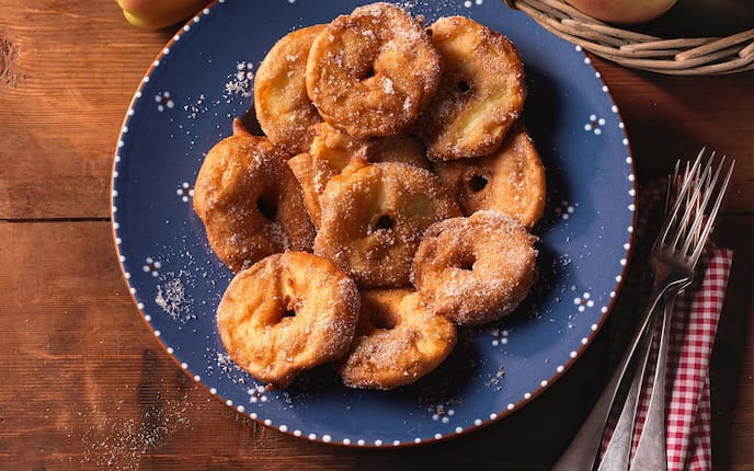 Apfelradeln, Zucker, Gabeln, Teller, Holztisch, Serviette, Korb