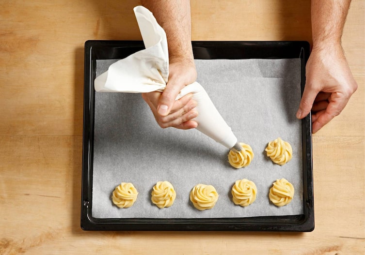 Teig, Teigrosetten, Spritzbeutel, Backblech, Holztisch