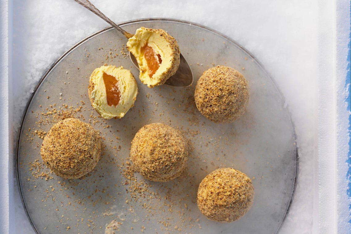 Kleine Eismarillenknödel auf einem flachen, grauen Teller, ein Knödel ist in der Mitte geteilt