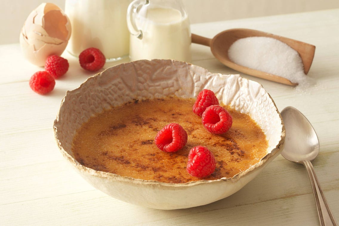 Geflammte Creme in einer Schüssel mit frischen Himbeeren auf einem Tisch