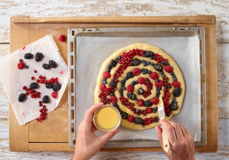 Ei-Milch Mischung, Beerenmix, Backpapier, Backblech, Brett, Pinsel, Hände