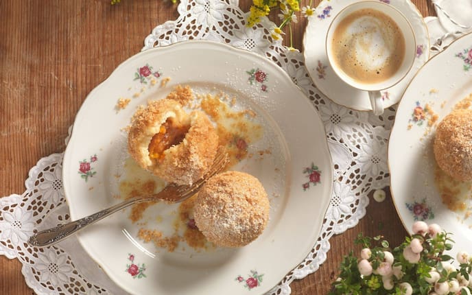 Marillenknödel aus Topfenteig, Brösel, Tischdecke, Blumen, Kaffeetasse