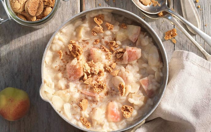 Milchreis, Pfirsich, Amarettinibrösel, Löffel, Serviette, Holztisch