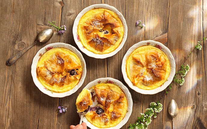 Millirahmstrudel in Schüsserl mit Blumenmotiv gebacken und auf einem Holztisch fotografiert.