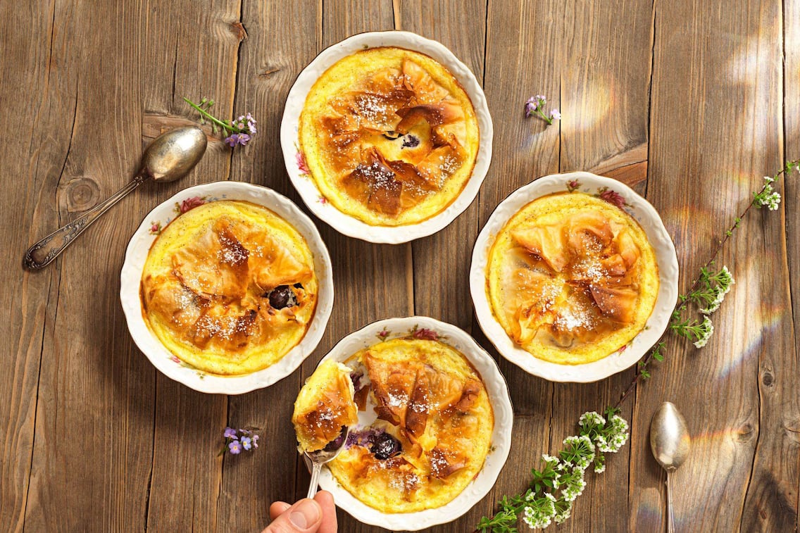 Millirahmstrudel in Schüsserl mit Blumenmotiv gebacken und auf einem Holztisch fotografiert.