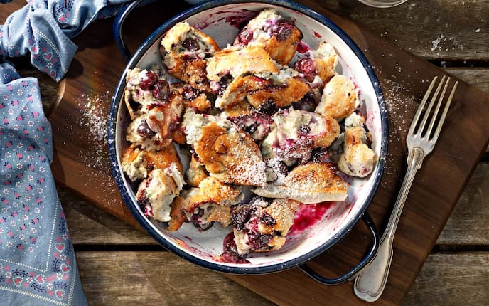 Schwarzbeeren, Schmarre, Holzbrett, Geschirrtuch, Gabel, Pfanne