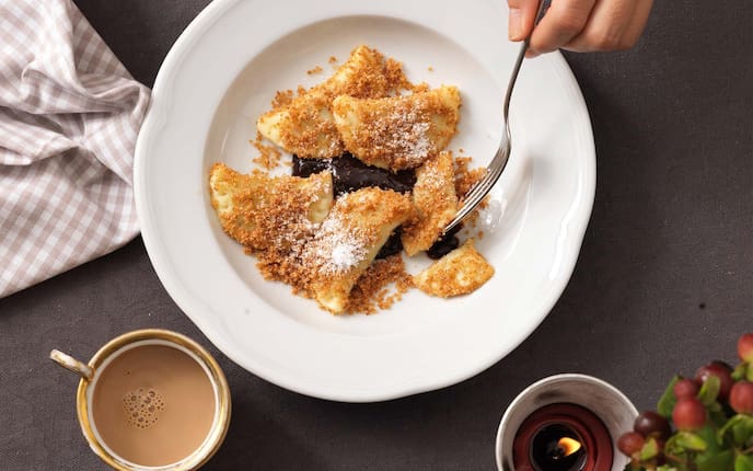 Powidltatschkerln, Kaffee, Brösel, Staubzucker, Kerze, Küchentuch, Gabel, Trauben