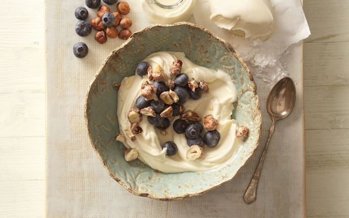Cremige Mascarponecreme mit karamellisierten Haselnüssen und Heidelbeeren in einer Schale serviert.