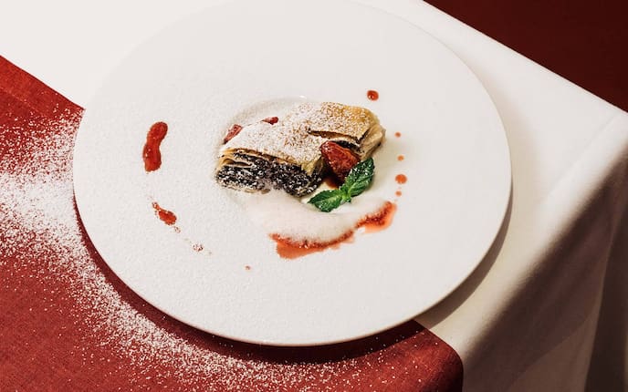 Mohnstrudel mit Feigen, Vanillezucker-Zimt-Schaum, Teller, Staubzucker, Minzblätter