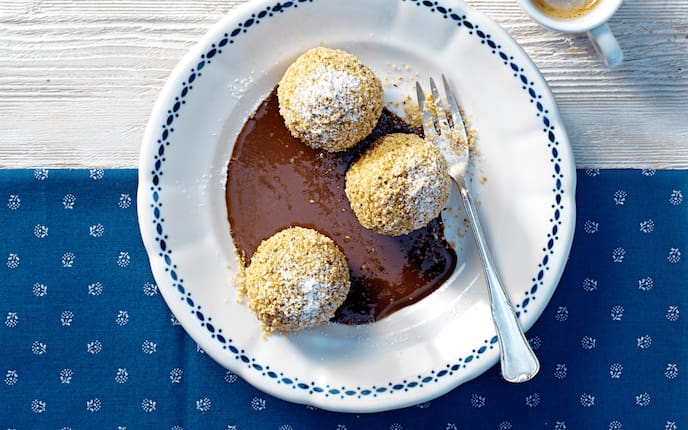 Ziegentopfenknödel mit Schoko-Chili-Sauce, Tischtuch, Espresso, Gabel, Teller, Staubzucker, geröstete Haselnüsse