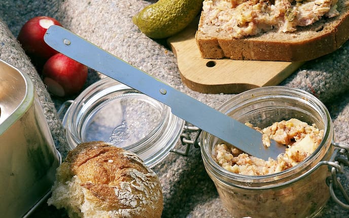 Traisentaler Fleischaufstrich, Holzbrett, Messer, Radieschen, Essiggurkerl, Brotscheiben