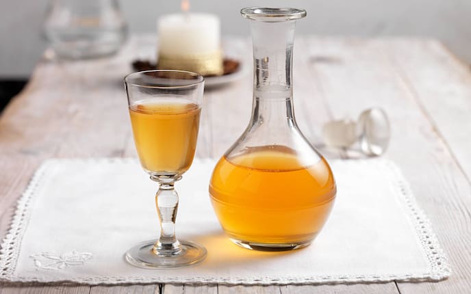 Anislikör, Glaskaraffe, Schnapsglas, Kerze, Tischdecke